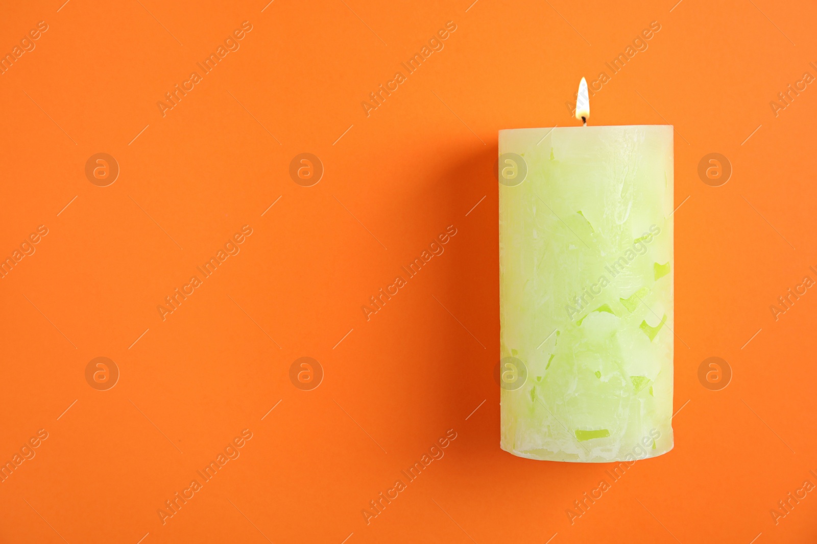 Photo of Alight wax candle and space for text on color background