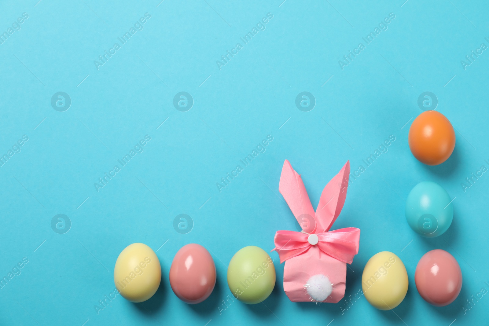 Photo of Flat lay composition of Easter bunny gift bag and dyed eggs on color background. Space for text