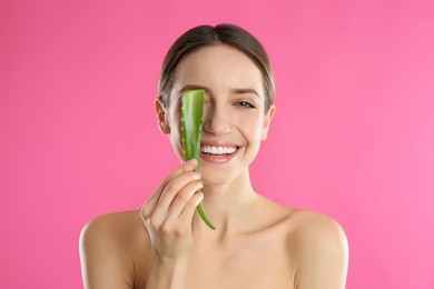 Photo of Happy young woman with aloe leaf on pink background