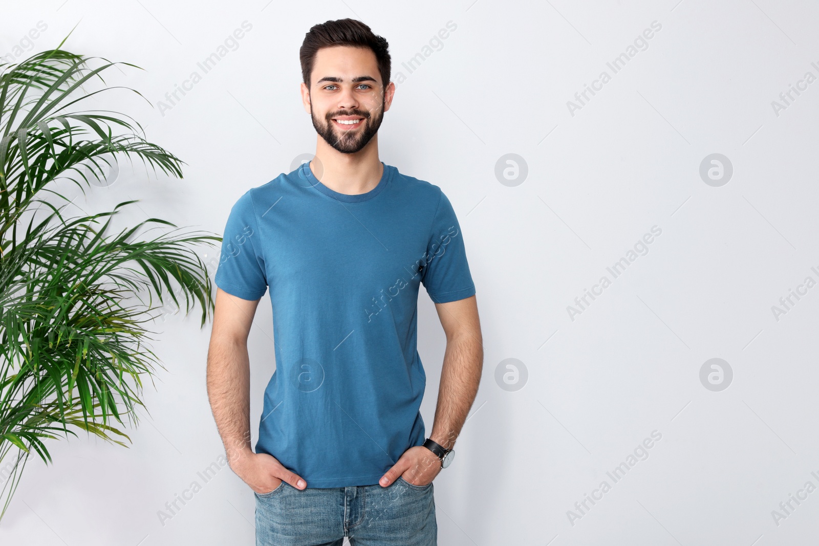 Photo of Young man in t-shirt near light wall. Mock up for design