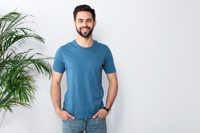 Young man in t-shirt near light wall. Mock up for design