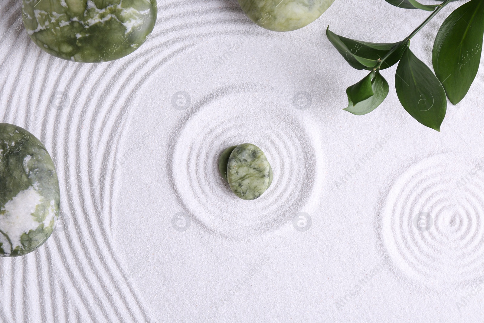 Photo of Zen concept. Stones, leaves and pattern on white sand, flat lay