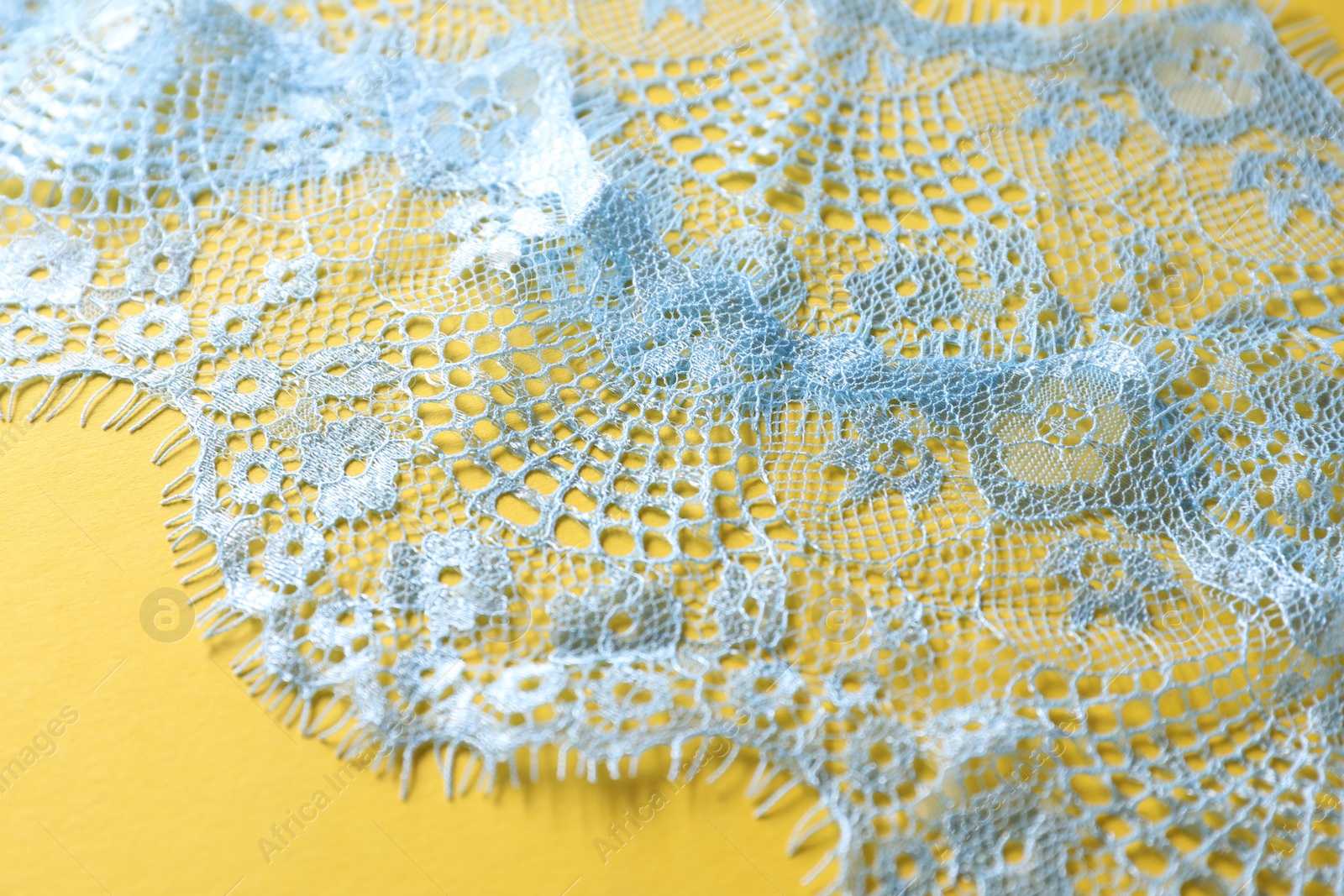 Photo of Light blue lace on yellow background, closeup