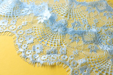 Light blue lace on yellow background, closeup