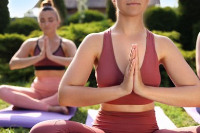 Photo of Young women practicing yoga on mats outdoors, closeup