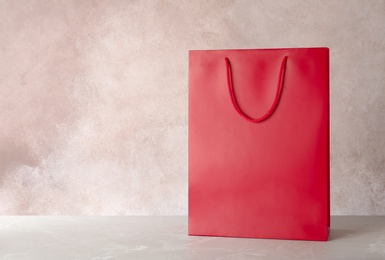 Mockup of paper shopping bag on table against color background