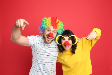 Photo of Couple with funny accessories on red background. April fool's day