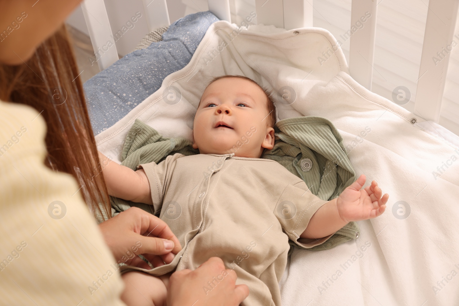 Photo of Mother with her cute newborn baby in crib, closeup