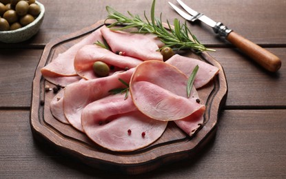 Photo of Slices of delicious ham with rosemary and olives served on wooden table