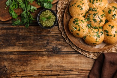 Photo of Traditional pampushka buns with garlic and herbs on wooden table, flat lay. Space for text
