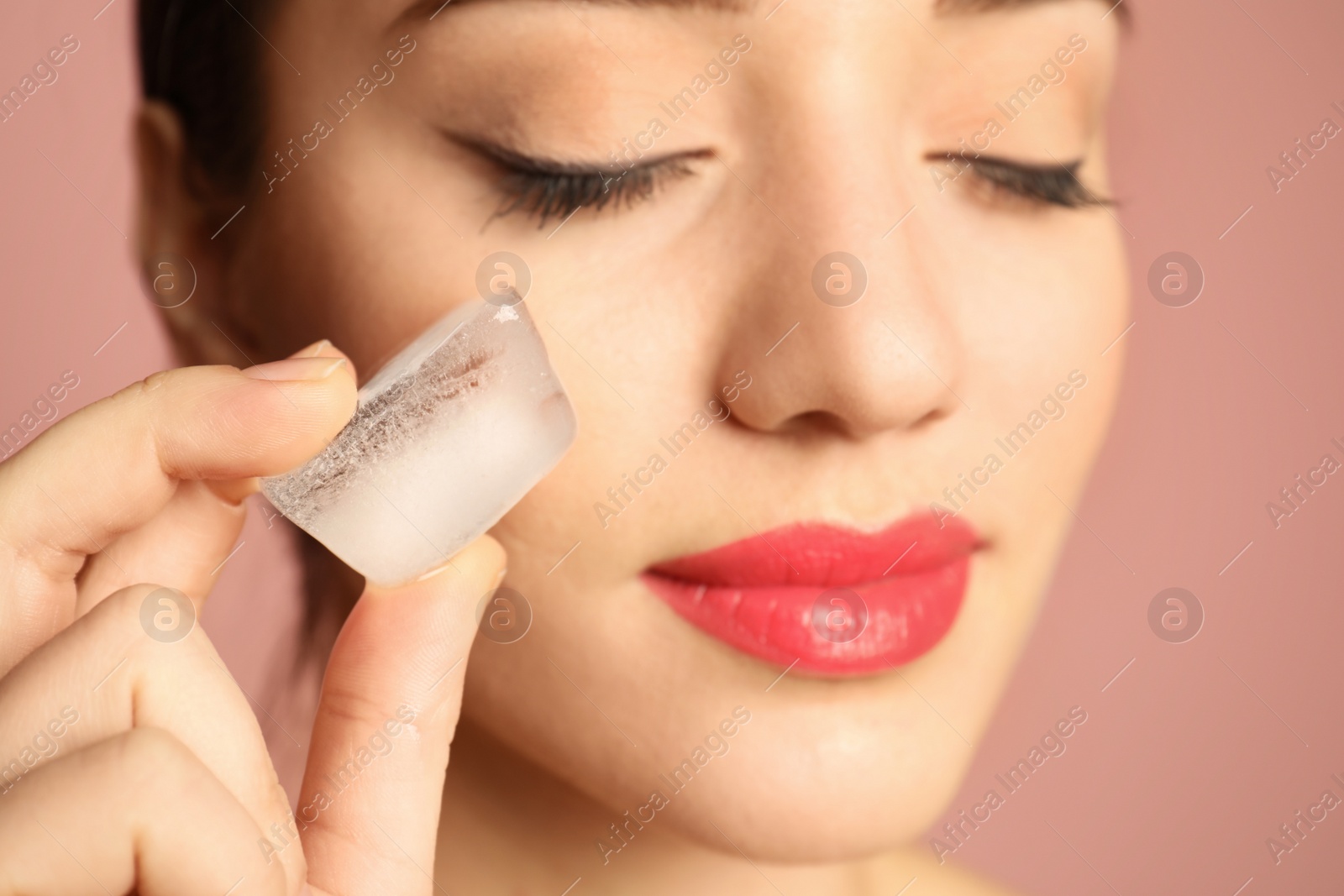 Photo of Young woman with ice cube on color background. Skin care