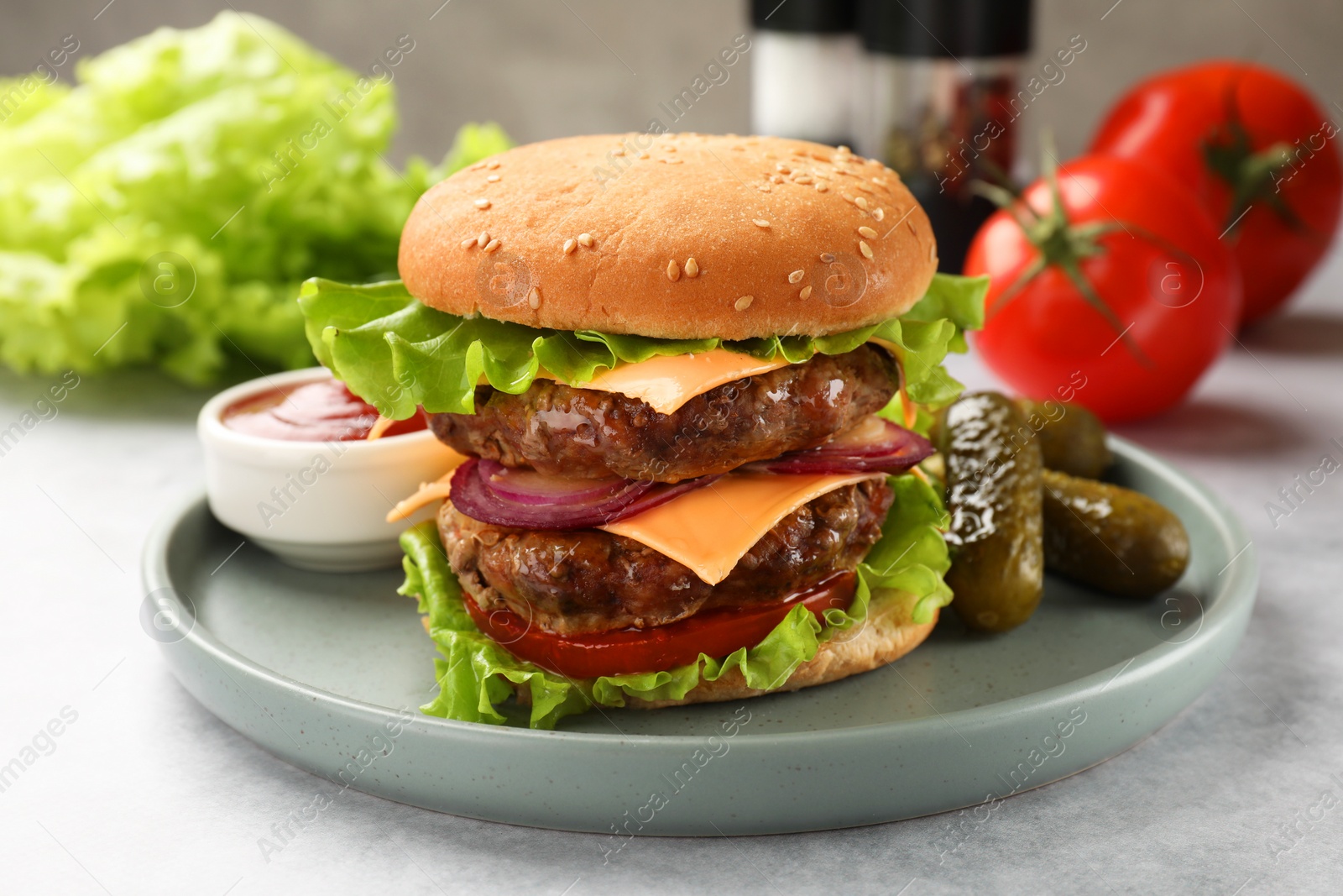 Photo of Tasty hamburger with patty, cheese and vegetables served on light gray table, closeup