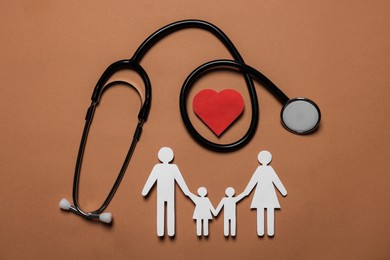 Photo of Paper family figures, red heart and stethoscope on brown background, flat lay. Insurance concept