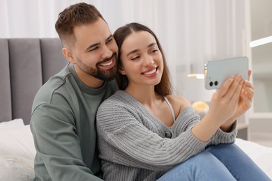 Happy young couple taking selfie in bedroom