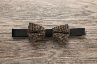 Stylish brown bow tie on wooden background, top view