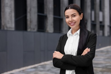 Portrait of smiling woman with crossed arms outdoors, space for text. Lawyer, businesswoman, accountant or manager