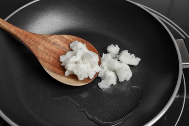 Frying pan with coconut oil and wooden spatula, closeup. Healthy cooking