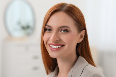 Photo of Portrait of beautiful young woman with red hair at home. Attractive lady smiling and looking into camera