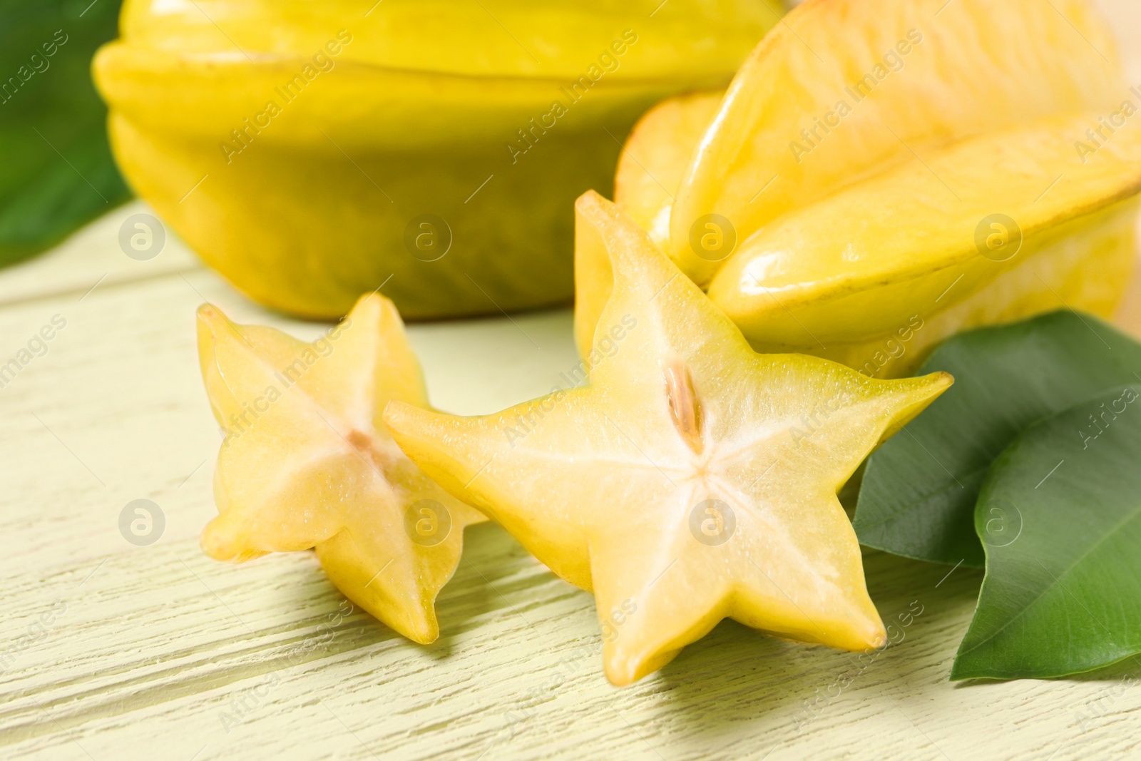 Photo of Delicious carambola fruits on yellow wooden table, closeup