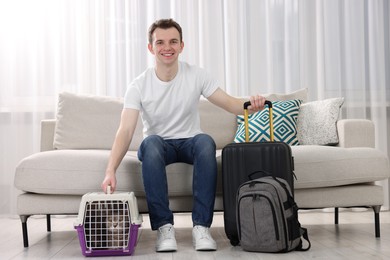 Travel with pet. Man near carrier with cute cat on sofa at home