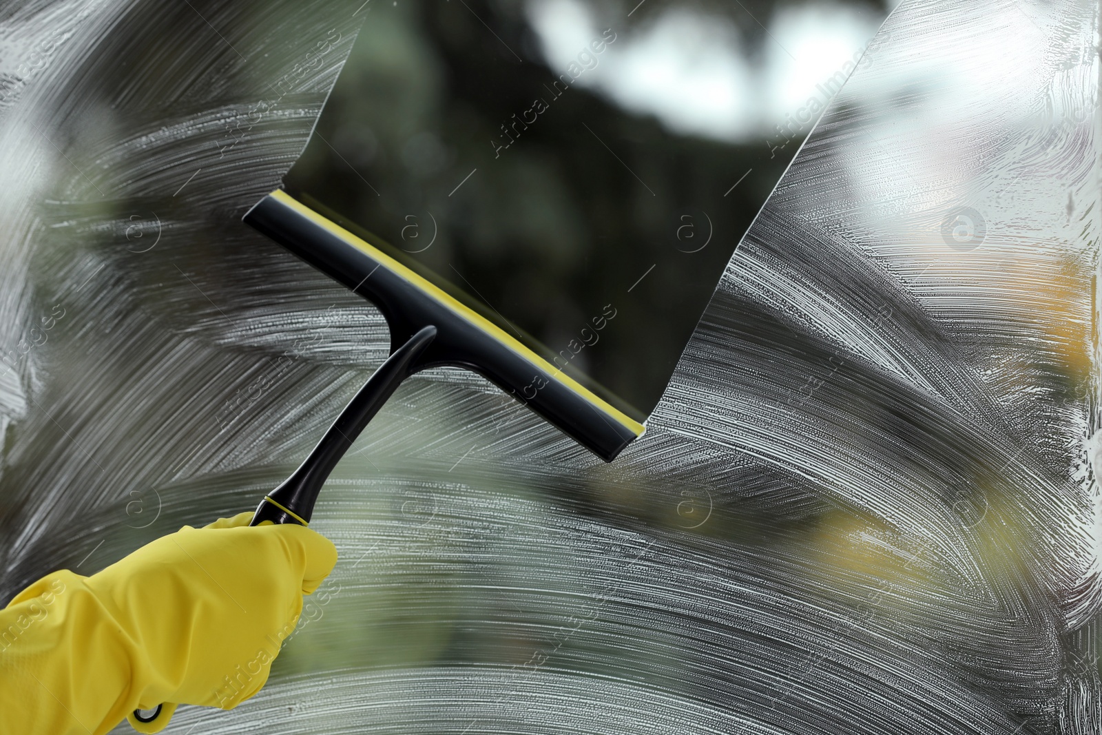 Photo of Woman cleaning glass with squeegee indoors, closeup