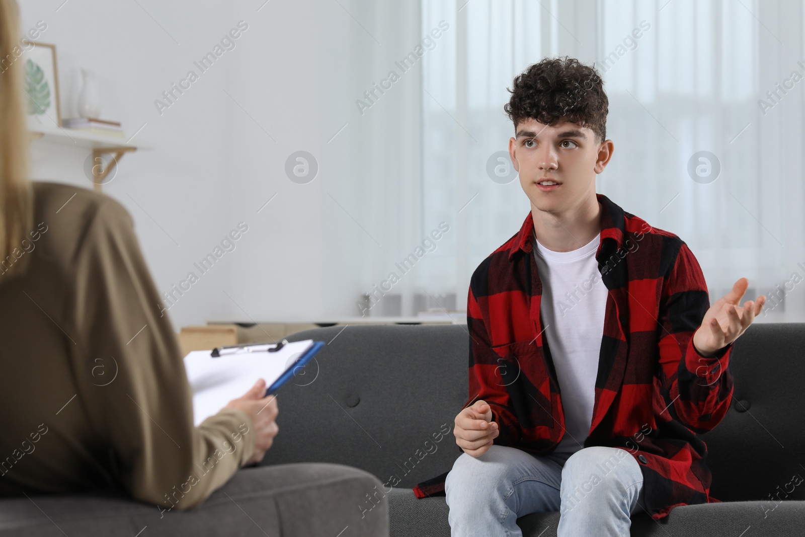 Photo of Psychologist working with teenage boy in office. Teenager problems