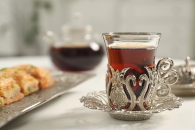Photo of Cup of delicious Turkish tea served on white table, closeup