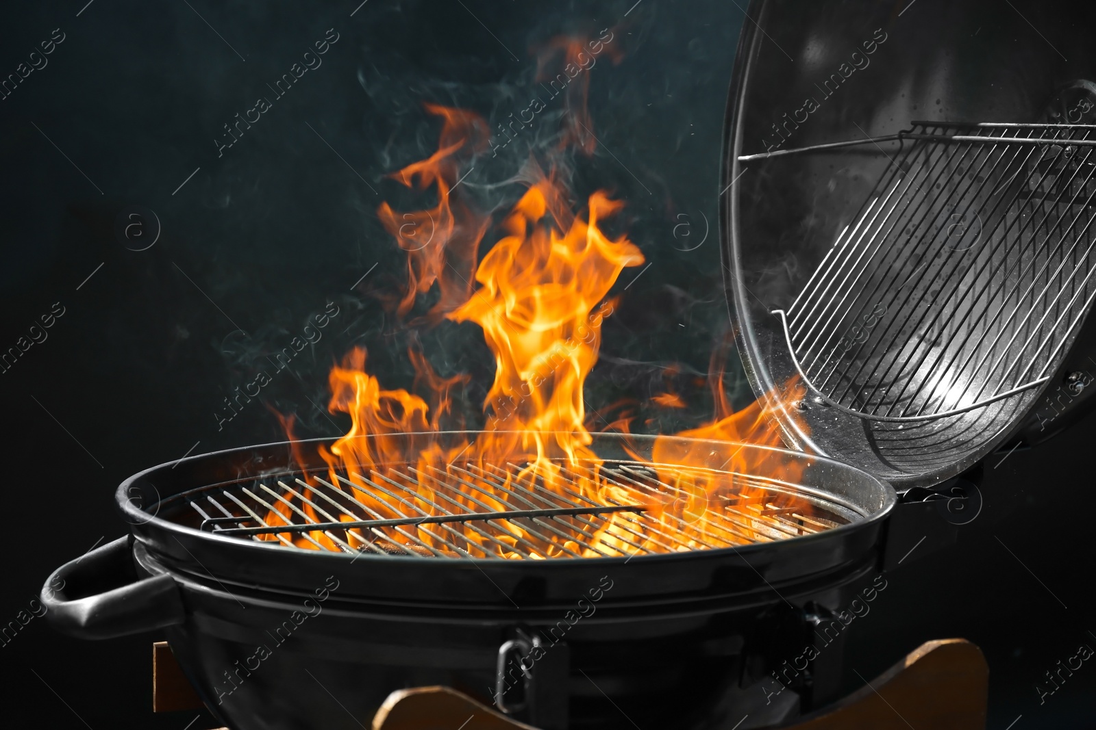 Photo of Modern barbecue grill with burning fire on dark background