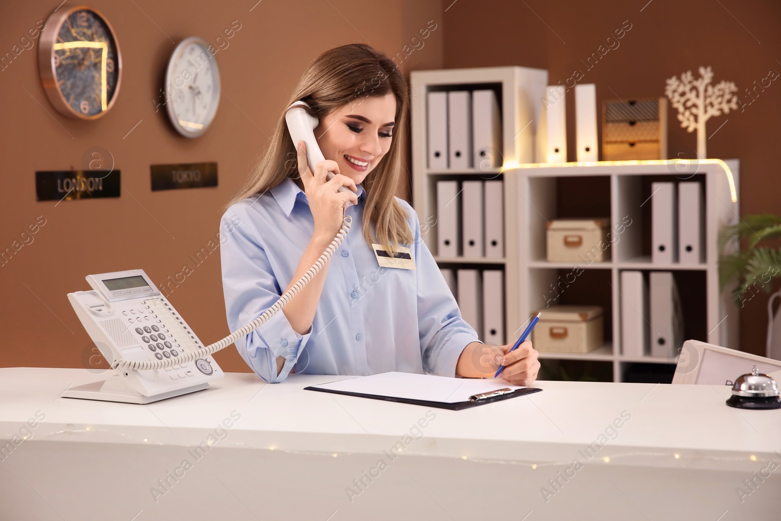 Photo of Female receptionist talking on phone at hotel check-in counter