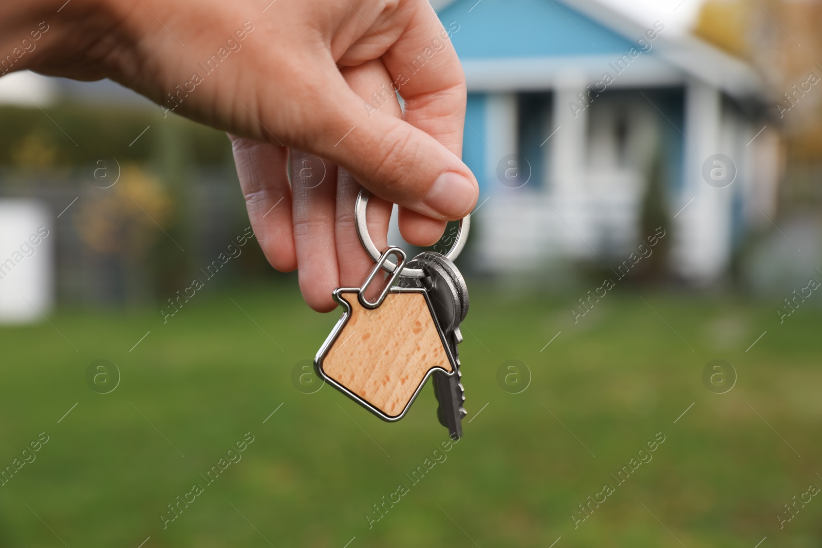 Photo of Woman holding house keys outdoors, closeup. Real estate agent