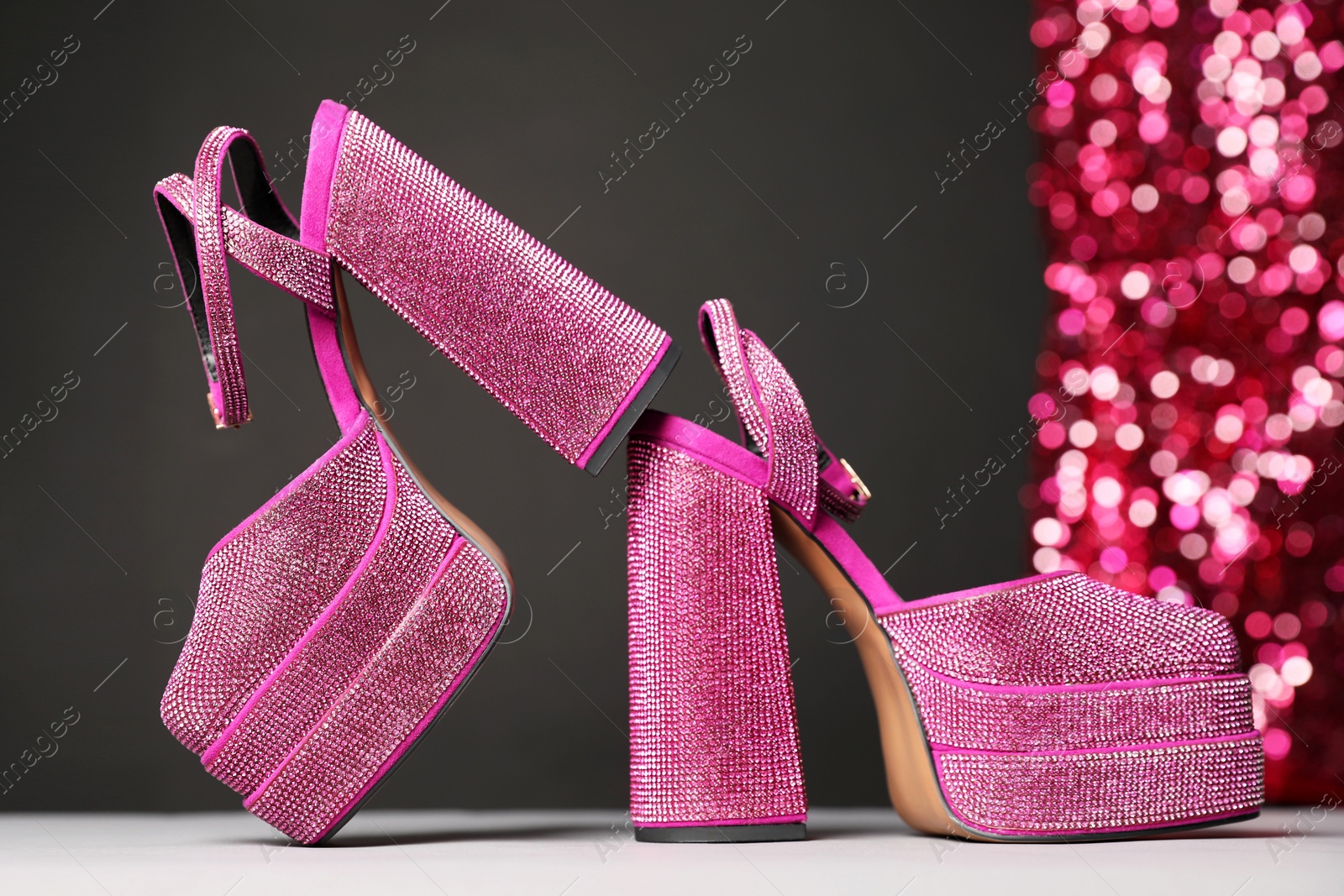 Photo of Fashionable punk square toe ankle strap pumps on light grey table. Shiny party platform high heeled shoes