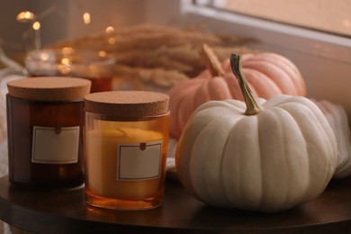 Beautiful pumpkins and scented candles on window sill indoors