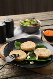 Photo of Plate with healthy dish high in vegetable fats and fork on wooden table, closeup