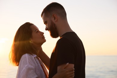 Photo of Happy young couple kissing near sea at sunset
