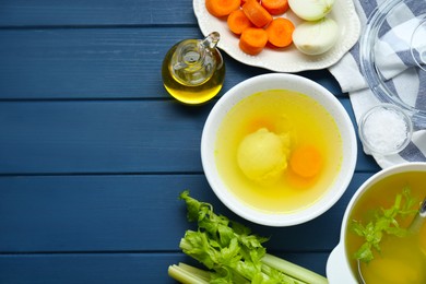 Photo of Delicious chicken bouillon and ingredients on blue wooden table, flat lay. Space for text