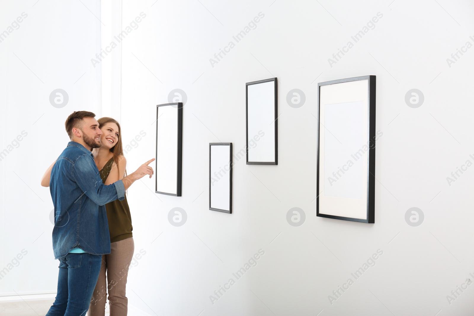 Photo of Young couple viewing exposition in modern art gallery