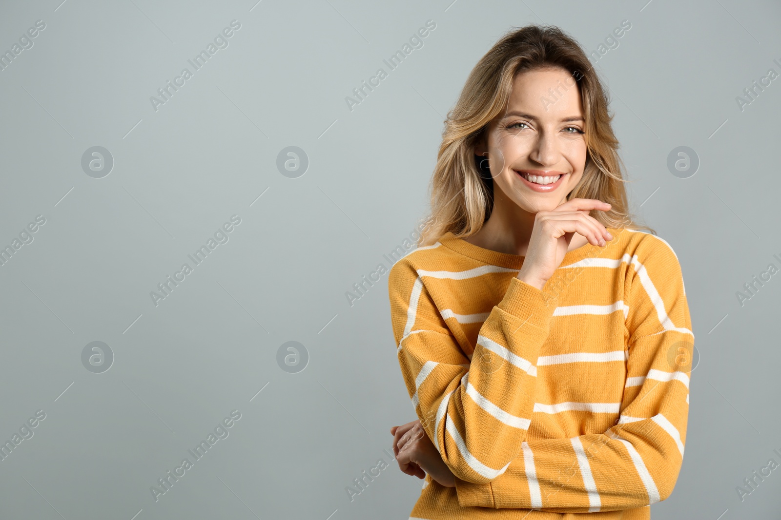 Photo of Portrait of happy young woman with beautiful blonde hair and charming smile on grey background. Space for text