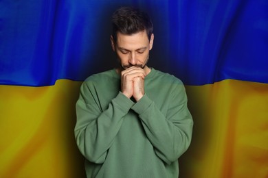 Image of Man praying against national flag. Stop war in Ukraine