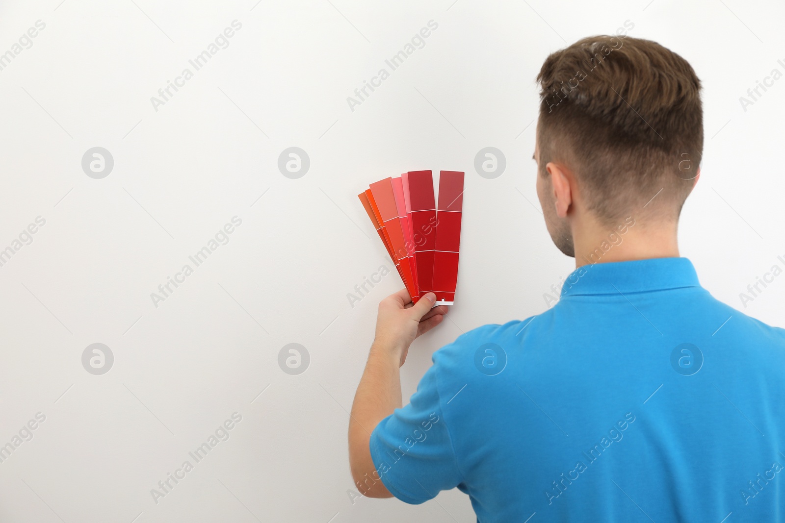 Photo of Man with palette choosing color for painting wall indoors. Interior design