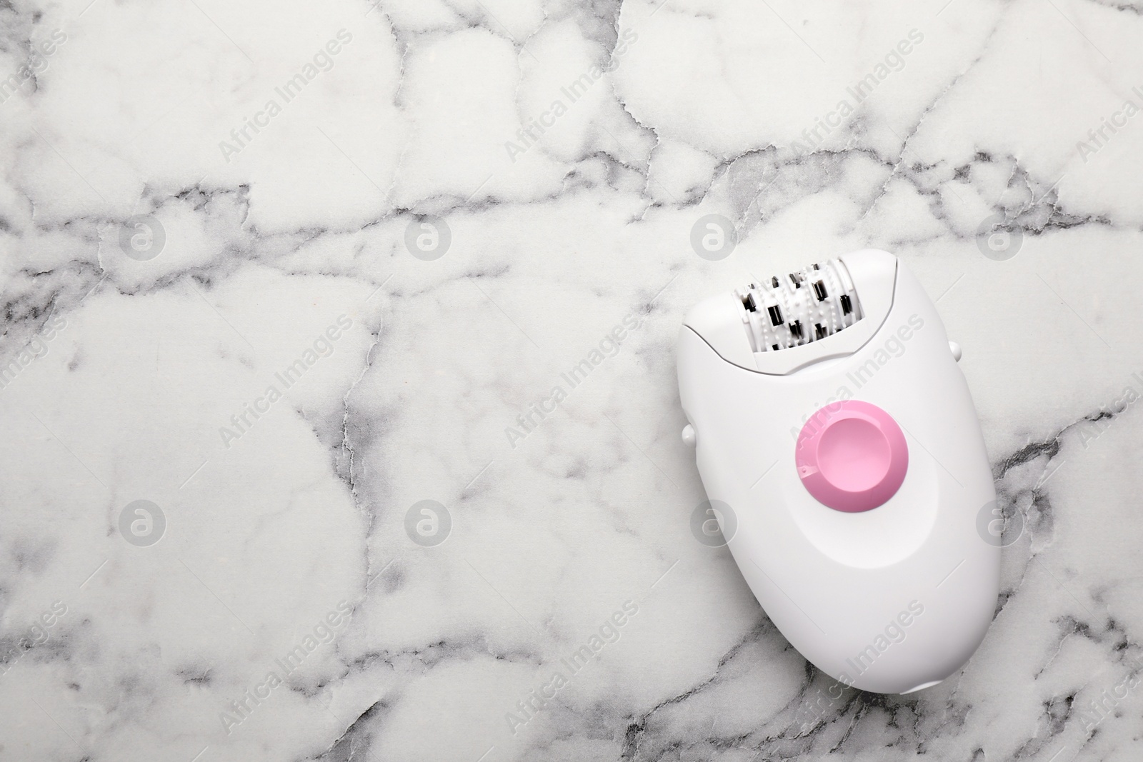 Photo of Modern epilator on white marble table, top view. Space for text