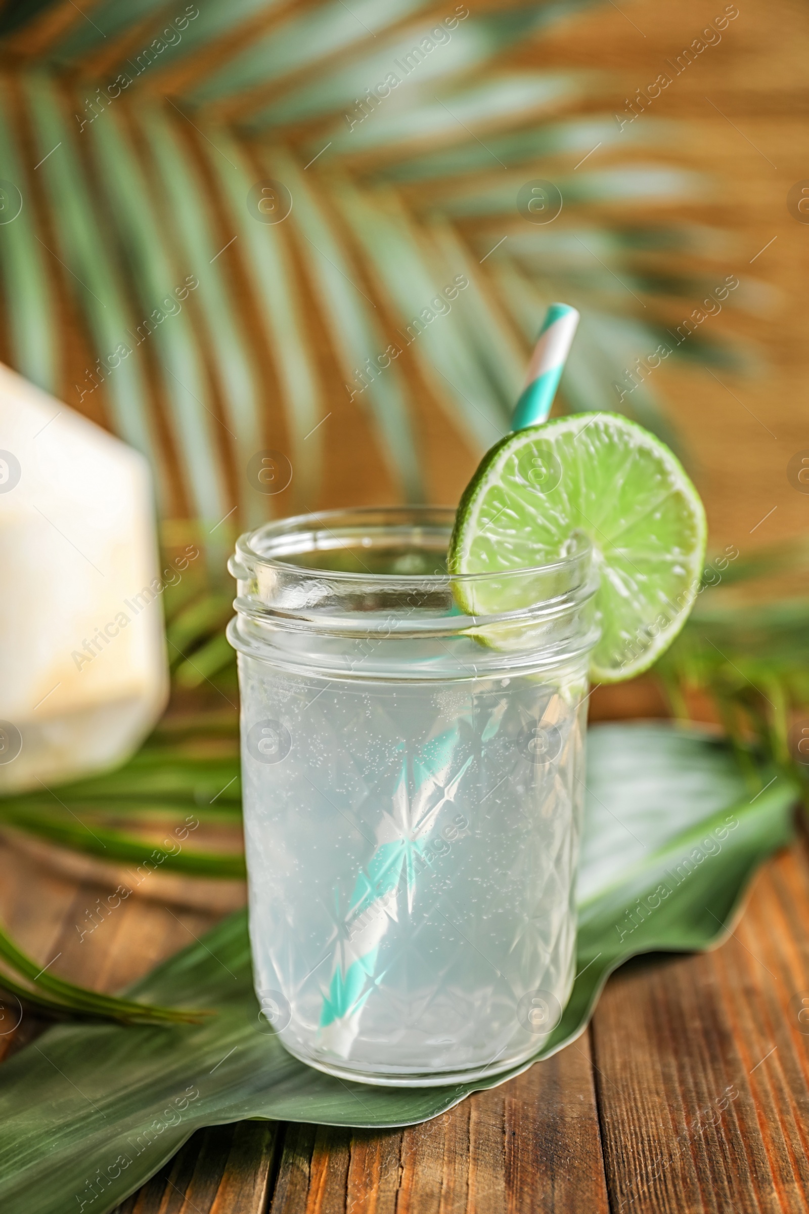 Photo of Jar with fresh coconut water and lime on wooden table