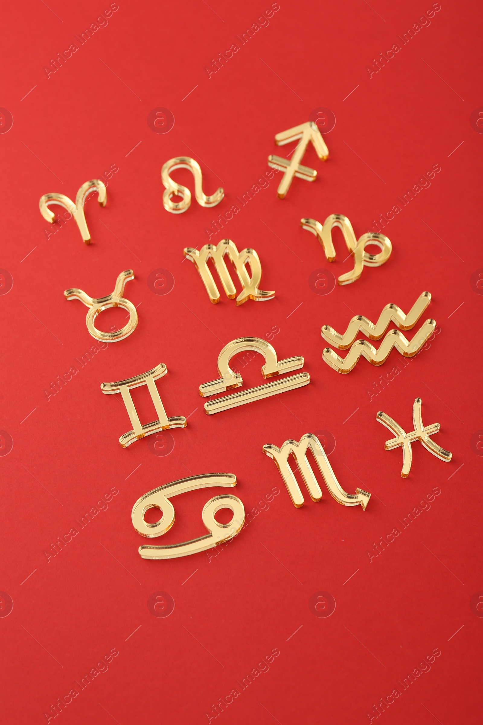 Photo of Shiny zodiac signs on red background, closeup