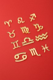 Photo of Shiny zodiac signs on red background, closeup