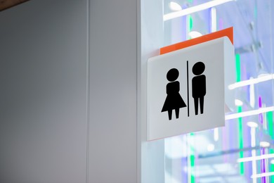 Image of White public toilet sign hanging on wall indoors