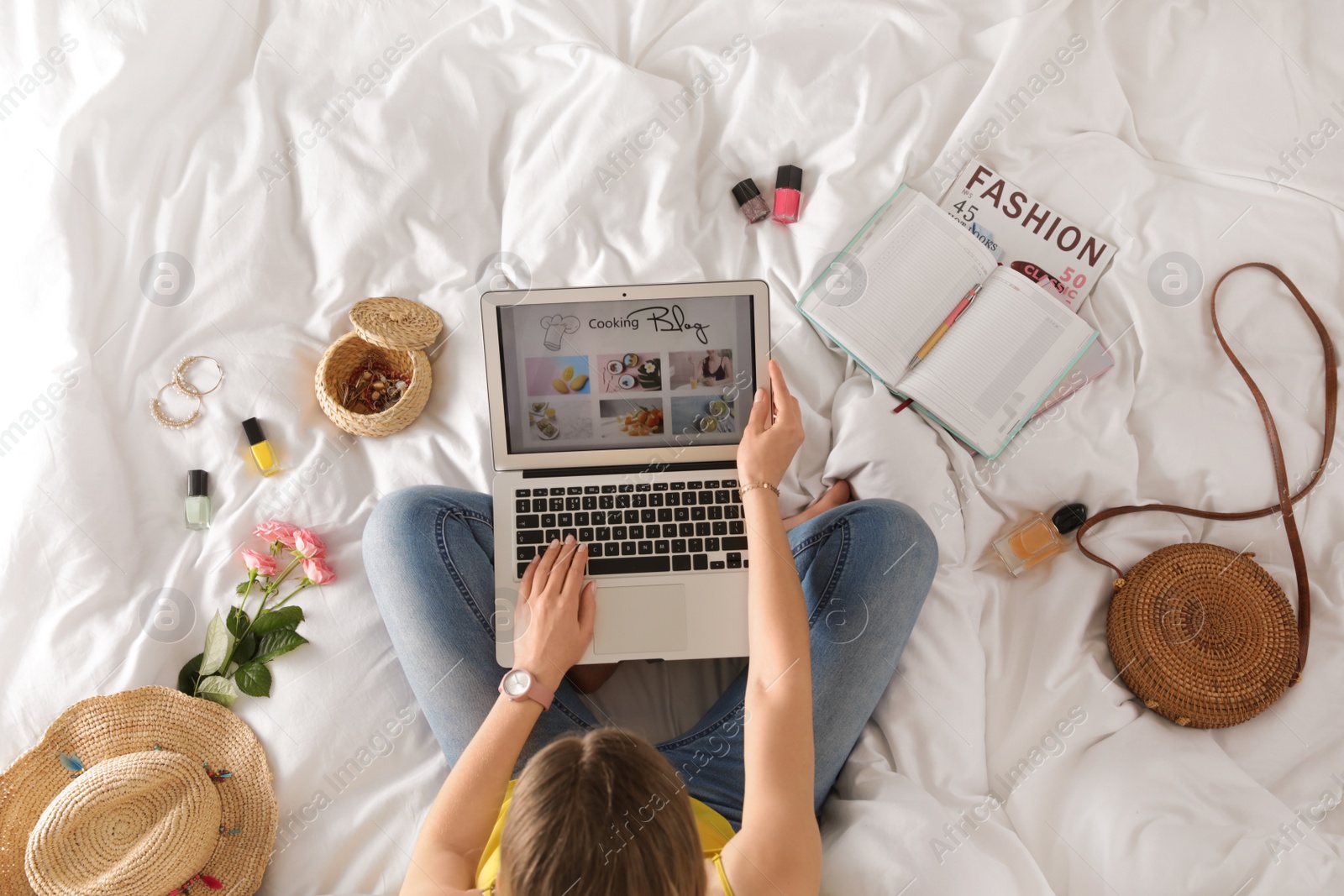 Photo of Woman and laptop with open cooking blog on bed, top view