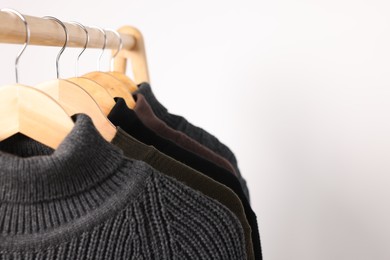 Photo of Rack with different casual sweaters on light background, closeup. Space for text