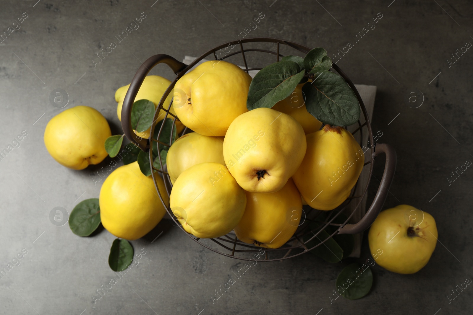 Photo of Fresh ripe organic quinces with leaves on grey table, flat lay