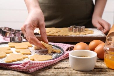 Photo of Woman making Christmas cookies at wooden table, closeup