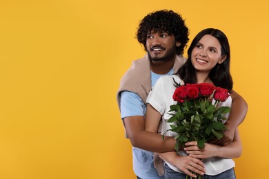 Photo of International dating. Happy couple with bouquet of roses on yellow background, space for text