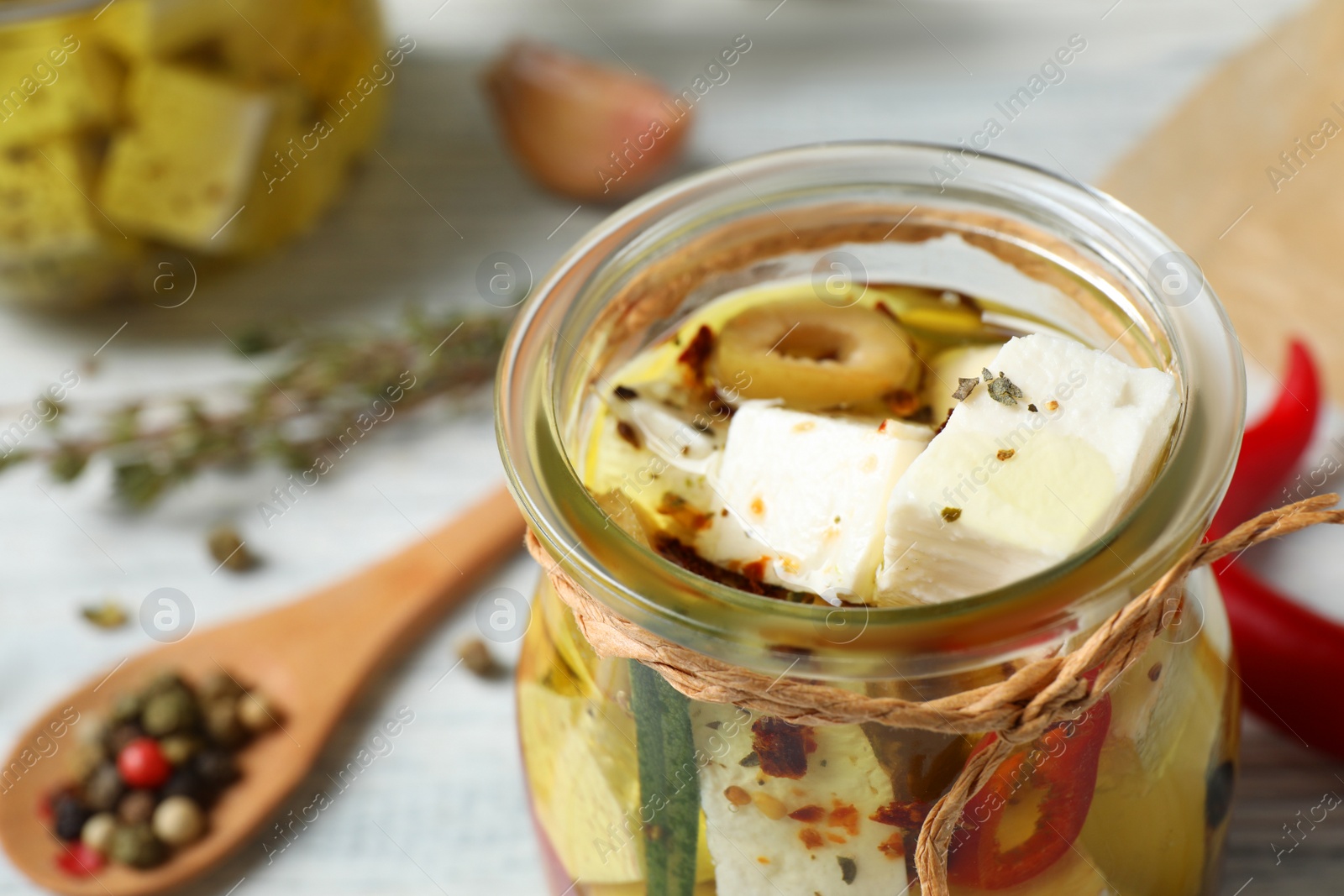 Photo of Jar with feta cheese marinated in oil on table, closeup. Pickled food